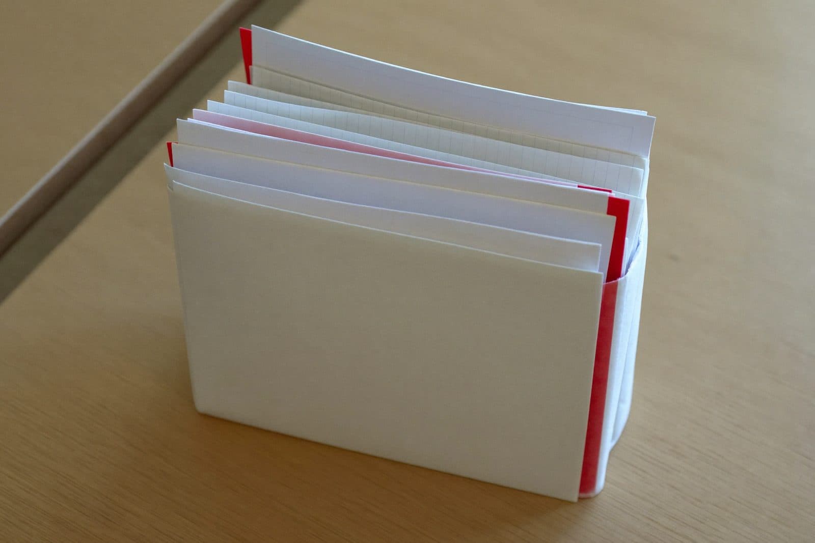 Dick gefüllte Dokumentenmappe mit herausschauenden Papieren auf einem Schreibtisch